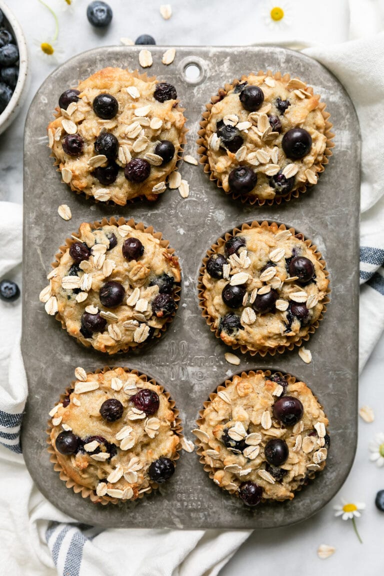 Overhead view of a muffin pan of freshly baked blueberry oatmeal muffins. 